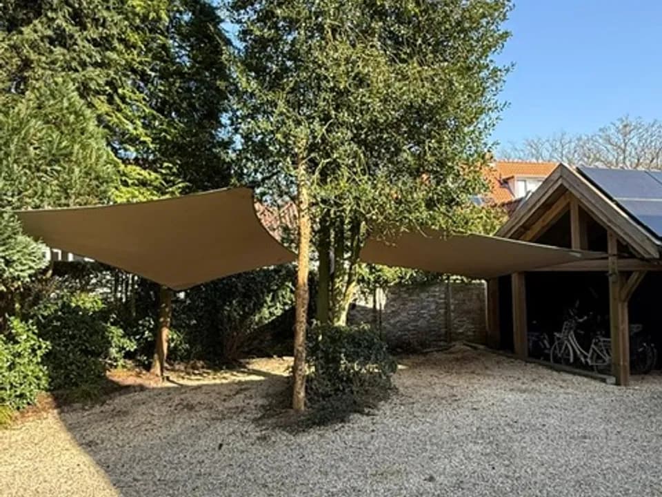 Lichte stretchtent-carport tussen volwassen bomen
