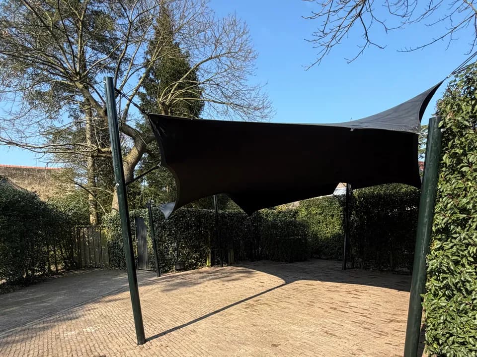 Donkere carport van stretchdoek boven een bestrate oprit