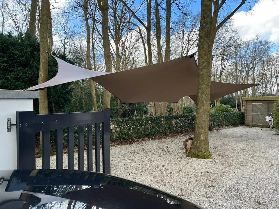 Zandkleurige carport op maat naast een woning