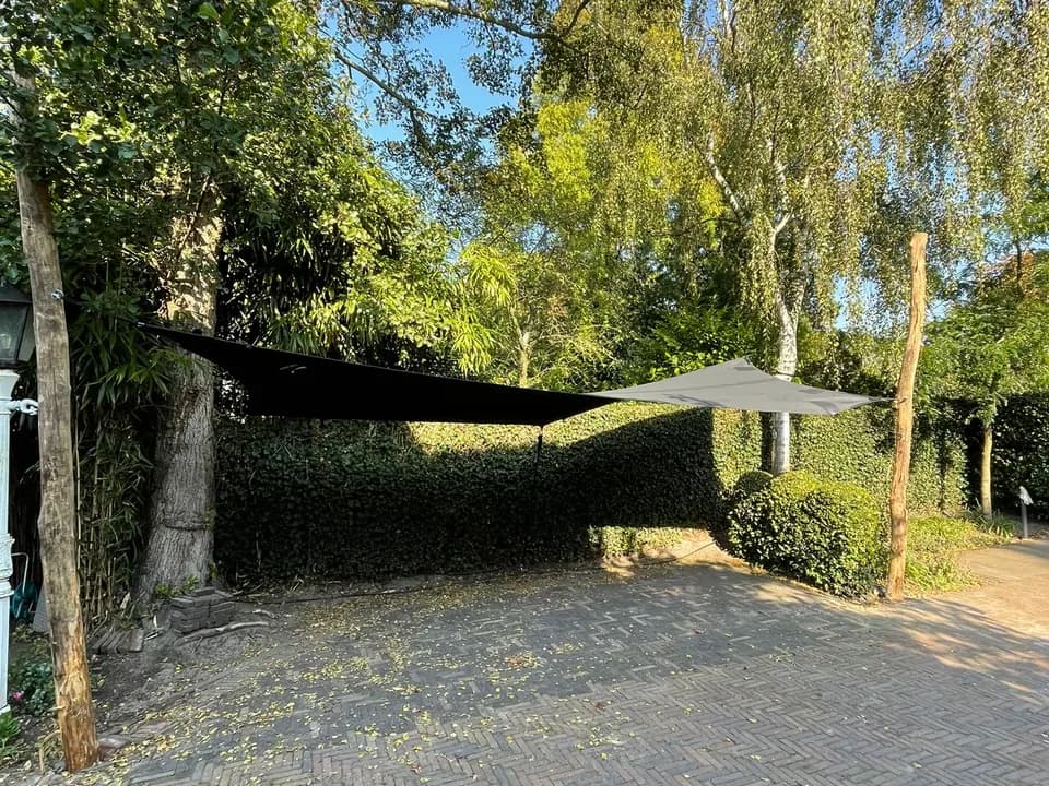 Donkere carport met organische lijnen in een groene tuin